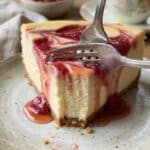 Close-up of a fork taking a bite out of a creamy slice of rhubarb cheesecake.
