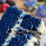 Close-up of a fork cutting into a moist slice of Royal Blue Velvet cake.