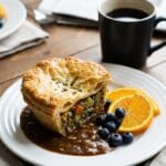 A serving of breakfast pot pie on a plate with fresh fruit and coffee.