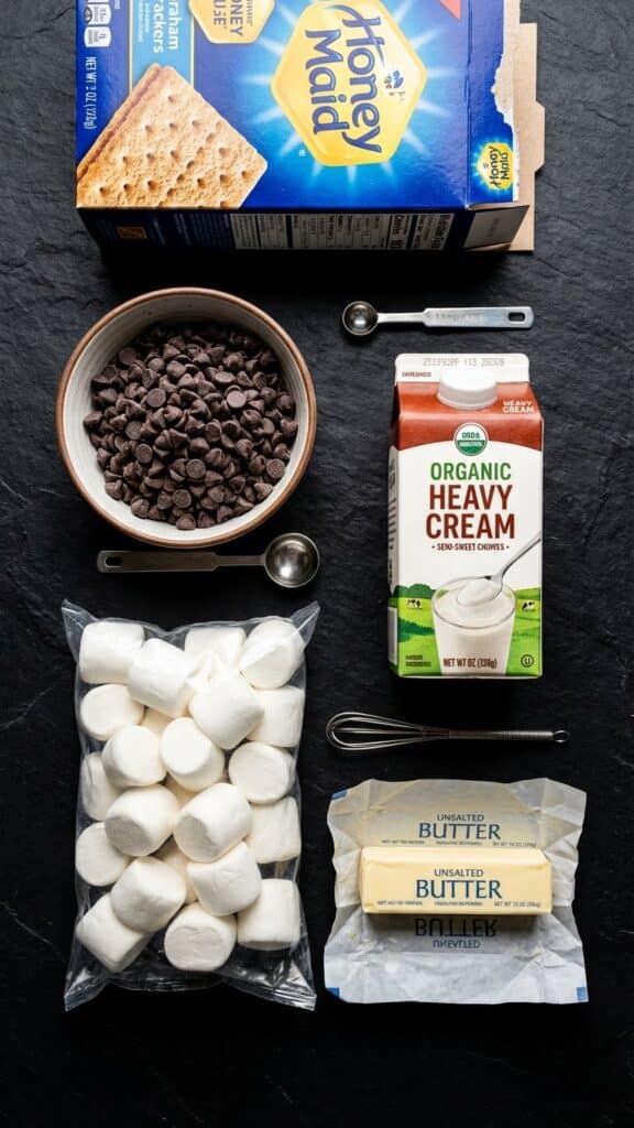 Flat lay of ingredients for s'mores pie including graham crackers, chocolate chips, and marshmallows.