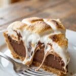 Close-up of a slice of s'mores pie with gooey toasted marshmallows on top.