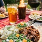 A serving of green pea salad on a picnic plate next to BBQ pork and iced tea.