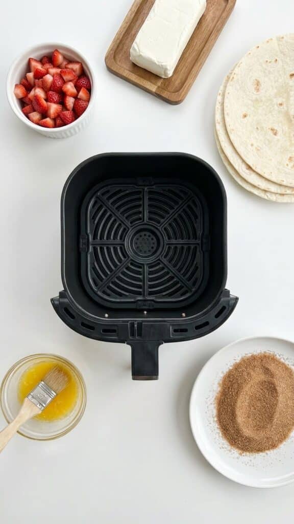 Ingredients for air fryer chimichangas including tortillas, strawberries, cream cheese, and a pastry brush.