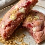 Close-up of a broken strawberry cheesecake cookie showing the soft interior.