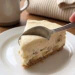 Close-up of a spoon scooping a bite of Banana Pudding Cheesecake showing banana chunks inside the filling
