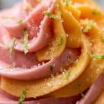 Close-up of pink and orange swirled frosting with sugar crystals.