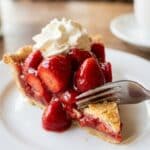 Close-up of a slice of fresh strawberry pie with whipped cream.