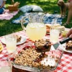 A pan of strawberry shortcake poke cake being served at a backyard picnic.