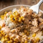 Close-up of a fork digging into a creamy street corn chicken bowl.