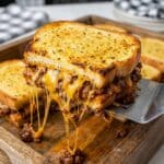 Close-up of a cheesy Texas Toast Sloppy Joe being lifted with a spatula.