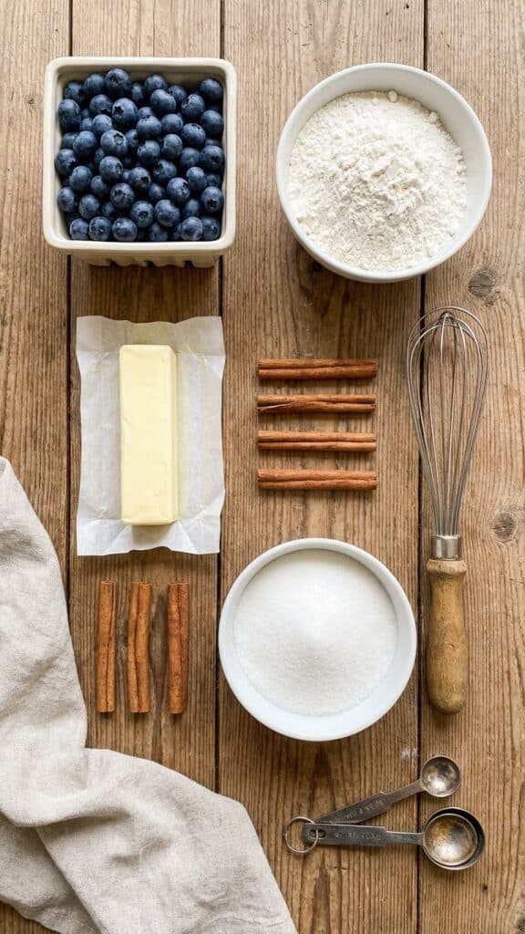 Flat lay of ingredients for blueberry buckle including fresh berries and cinnamon.