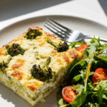 Slice of Broccoli Cottage Cheese Bake served on a plate with a fresh side salad.