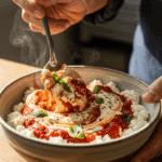 A person stirring a warm cottage cheese pizza bowl with a spoon, mixing the cheese and sauce together.
