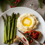 Plated stuffed chicken dinner with asparagus and white wine in a candlelit setting.