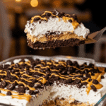 Glass baking dish of Heaven in a Bowl dessert being served with a spatula, garnished with cookies.